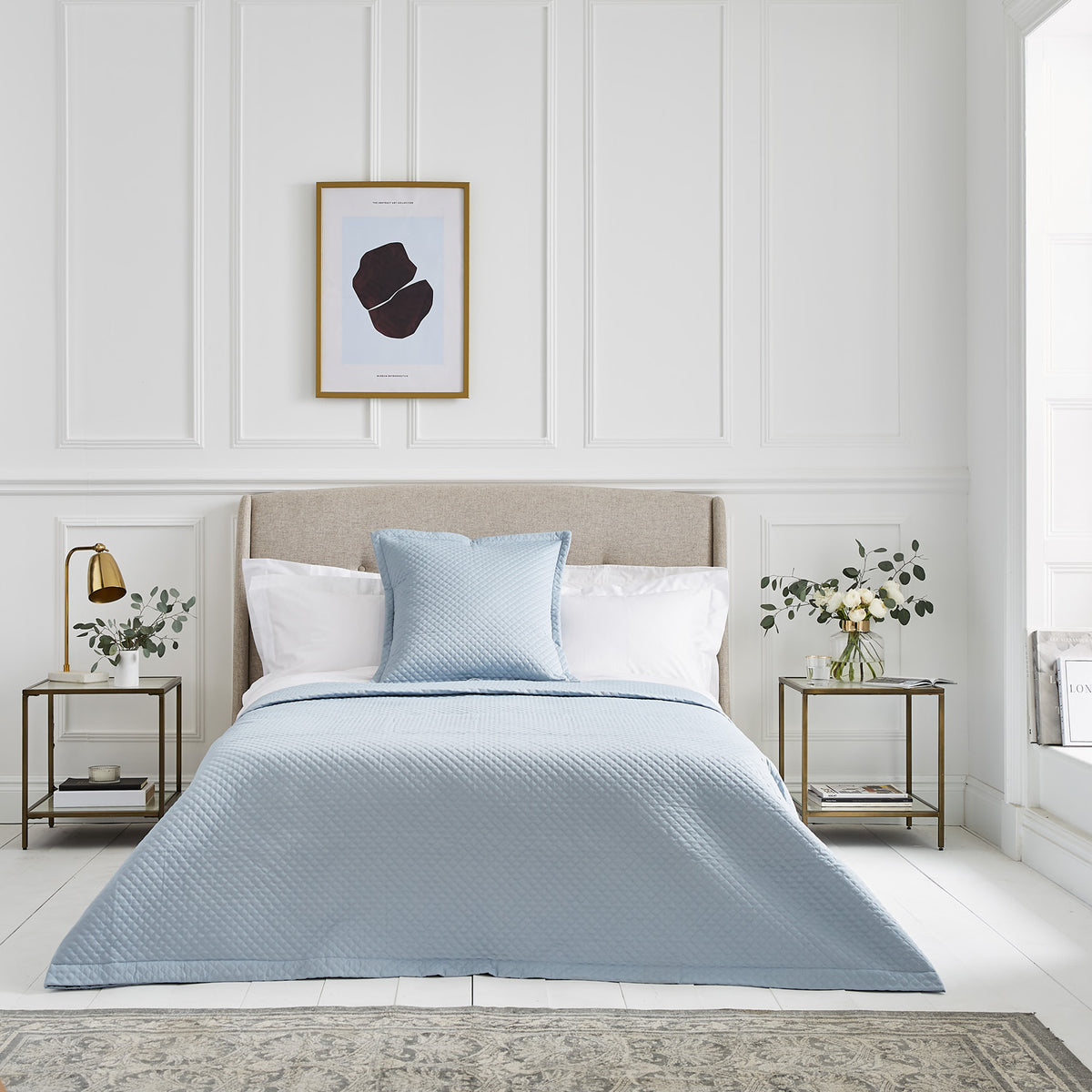 Blue Grosvenor quilted bedspread layered over white hotel-style bed linen